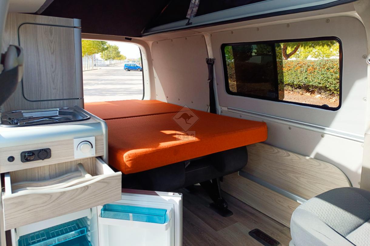 Cama camper extendida y nevera abierta