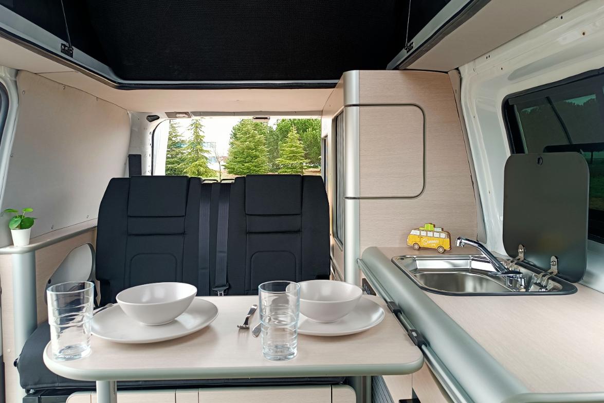 Camper Ford Melbourne en alquiler con la mesa puesta vista a los asientos traseros