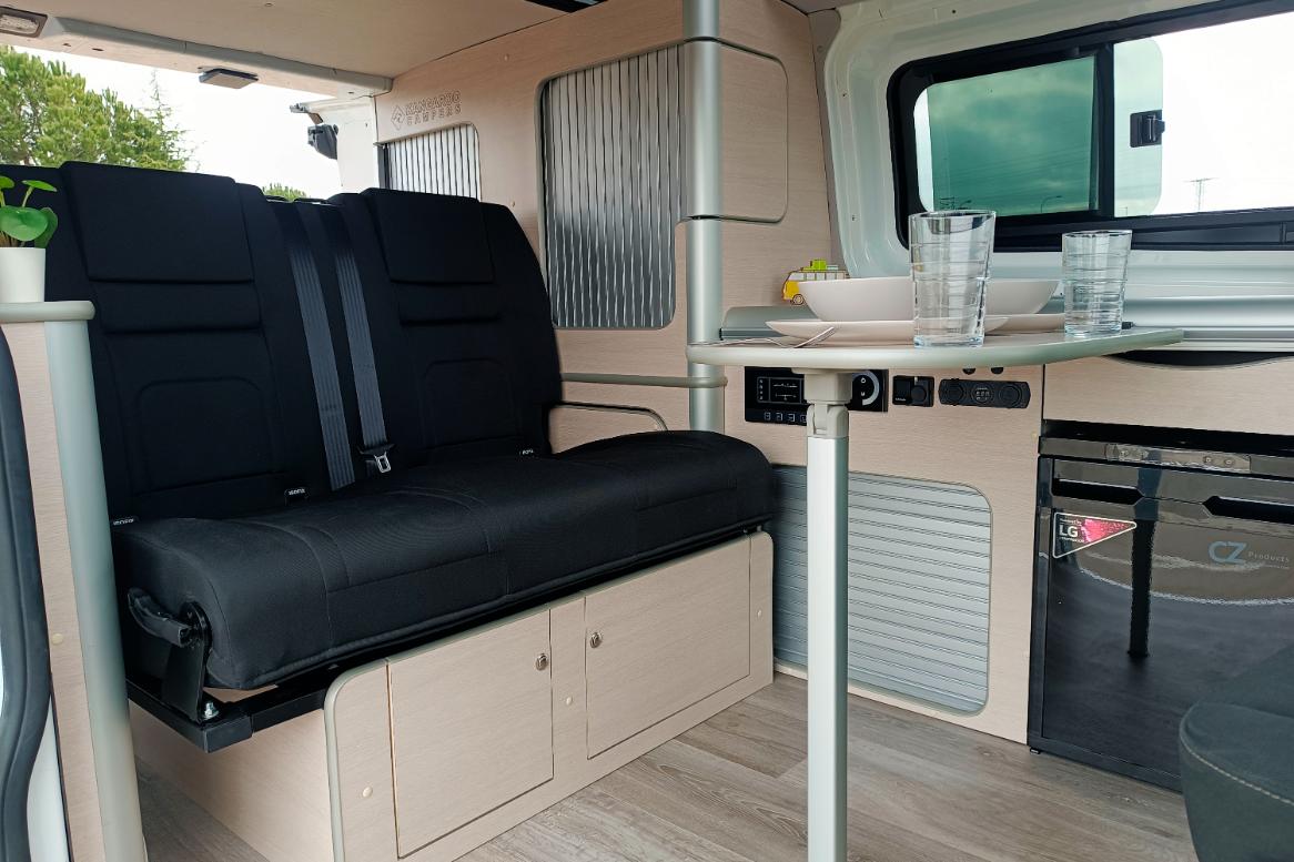 Camper Ford Melbourne en alquiler con la mesa puesta asientos traseros y almacenaje