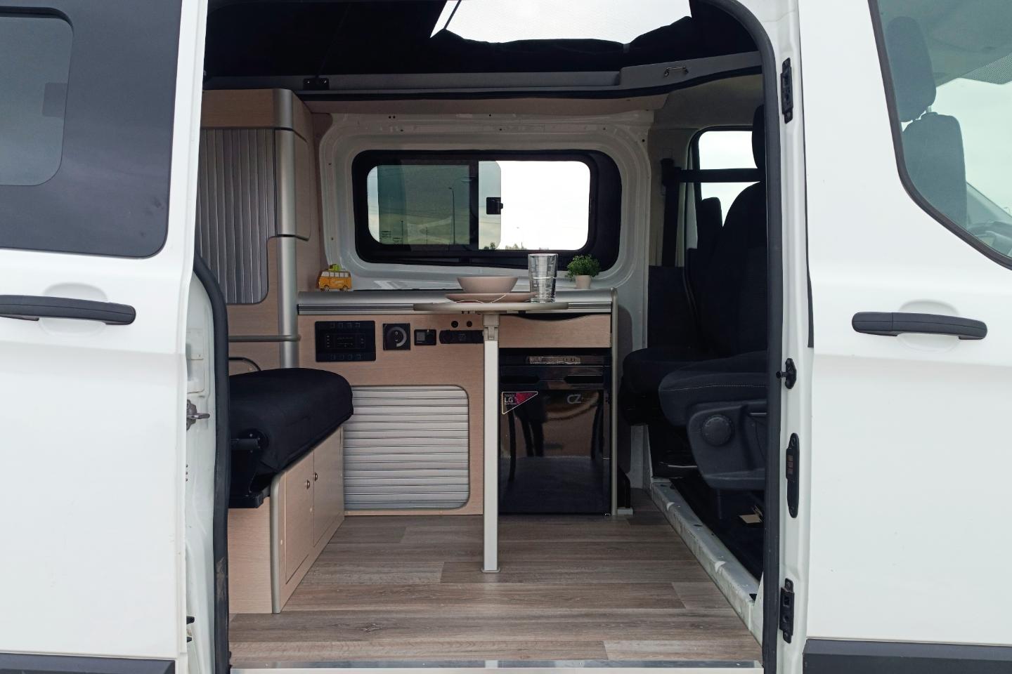 Camper Ford Melbourne en alquiler vista lateral interior con mesa abierta